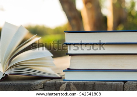Pile of closed books with open book on wooden background.