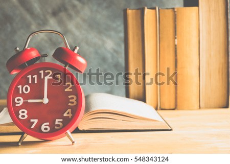 Vintage red alarm clock and books on wooden table