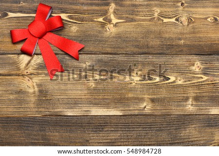 decorative valentine red bow in left corner on brown vintage wooden background, copy space