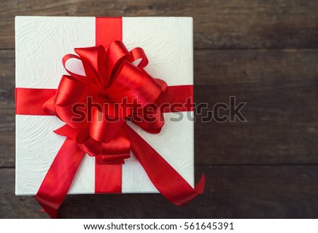 gift box with red bow on wood table, top view 
