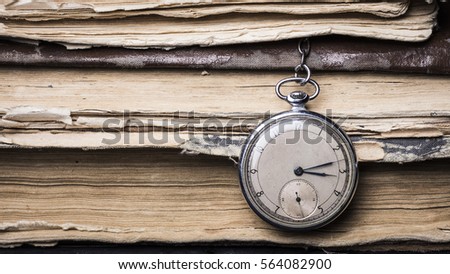Decaying clock on the background of old shabby wise books.