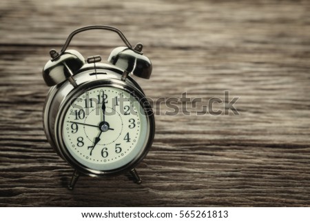 Clock at 7 O'clock in the morning with vintage style alarm clock on a wooden table.
