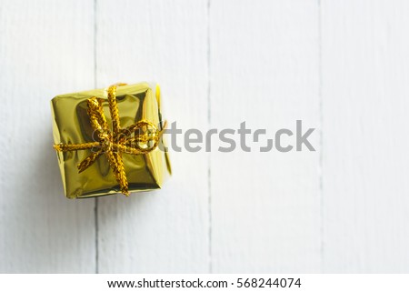 little golden gift box on white wood table background