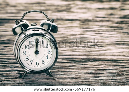 Clock at 12 O'clock in the morning with vintage style alarm clock on a wooden table. Concept  retro or vintage style.  