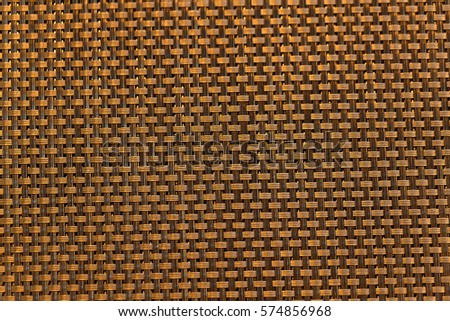 A dark colored background of a tissue of light, yellow, beige color with square, quadratic ornament 