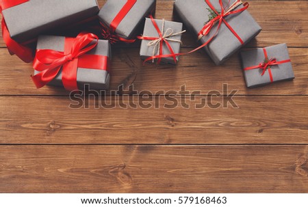Presents for any holiday concept. Gift boxes, top view with copy space on wood table surface background. Border of packages with red satin ribbons for christmas, valentine day or birthday