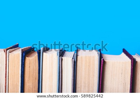 Books stacked horizontally and isolated on blue background.