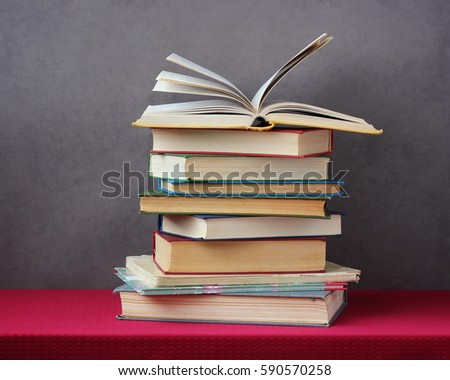 stack of books on the table with a red tablecloth. literature, reading, open book.
