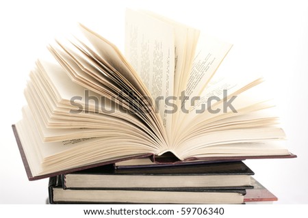 Open book on stack of various books against white background.
