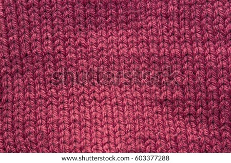Texture of dark pink knitted fabric. Stranded threads. Cloth of warm winter clothes. Blurred.