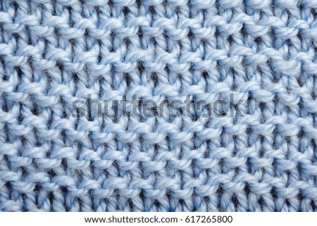 The texture of a blue knitted woolen fabric, closeup.