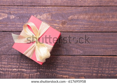 red and gold gift box on wood background.