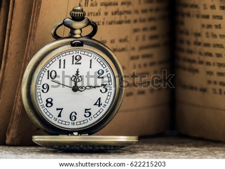 Pocket watch and old book on the table