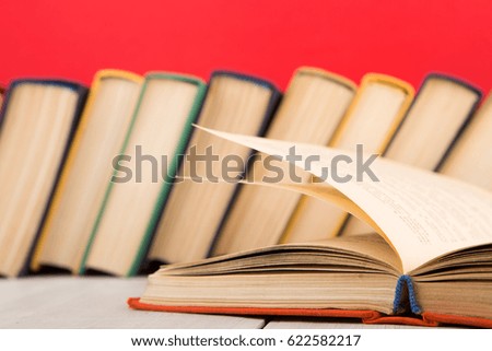 education and wisdom concept - open book on wooden table, red background