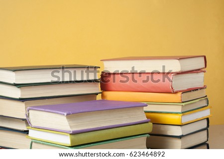 Stack of books on yellow wall background. Copy space for text. Back to school. Education concept.