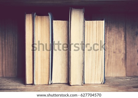 Old books in a row on a wooden bookshelf
