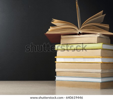 Stack of books on wooden table on black background.Back to school.Education concept.