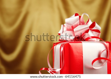 Christmas gift in a red box with a silver bow on golden background