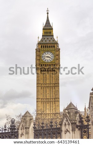 Historic Big Ben Tower with old clock giving the time against cloudy background