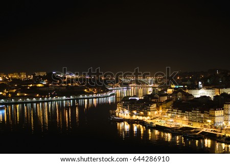 The city lights and reflections in the Douro river at night in Porto, Portugal.