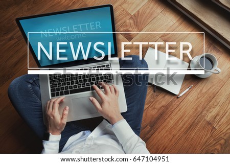 Top view of young woman sitting on the wooden floor with laptop and coffee with newsletter inscription in the foreground