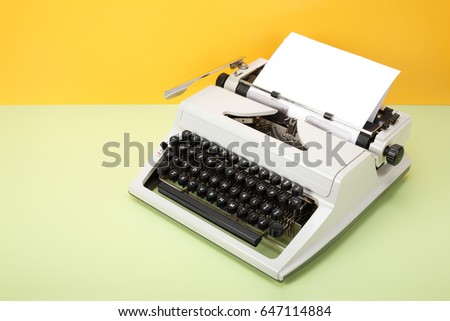 Vintage objects - Retro Typewriter on a yellow background and a green table.