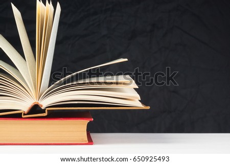 Old books on the table, on a black background, white table