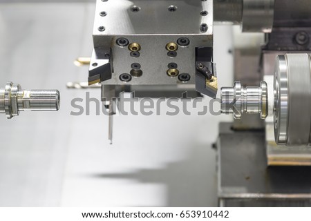 The double spindle type of  CNC lathe machine (Turning machine) with  the metal rod and   turning tool .The hi-technology machining concept.