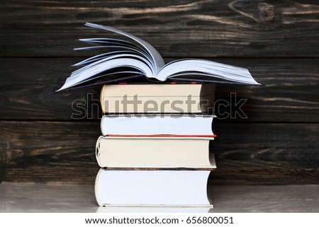 Education concept. Stack of books close up  with rustic wooden background. One book is open