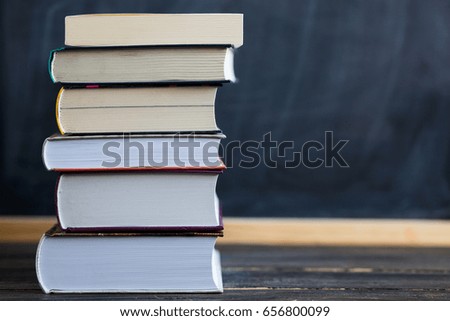 School concept. Back to school concept. Stack of books close up on wooden desk with chalkboard as background