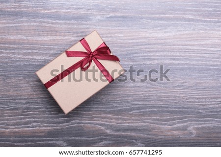 Beautiful gift box for present with red bow and ribbons on wooden background.