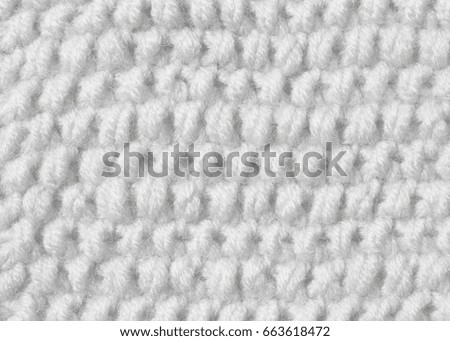 Texture of a knitted cloth from white woolen threads. Background with a pattern of honeycomb pattern.