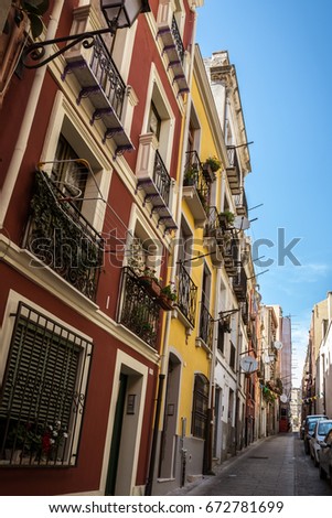 Colorful houses in the narrow streets of Cagliari in Sardinia, Italy. Facades of houses in red and yellow, beautiful blue sky on a sunny day. Nobody in the scene.