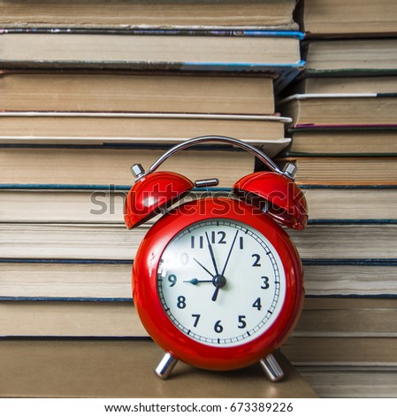 red alarm clock showing nine o'clock on stack of old books background, selective focus,  back to school idea, sign, symbol, concept. time management. education background