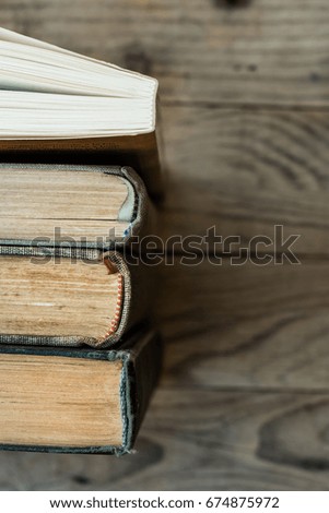 Old and new books arranged in a row, top view of spines, aged wood background, school, education, learning, reading concept, copyspace