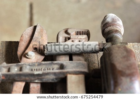 Close up of old used rusty tools on wooden table against brown grey wall