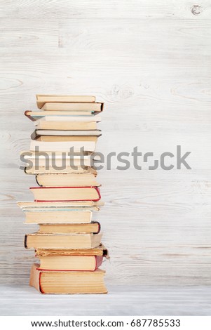 Stack of old books in front of wooden wall. School background. Education backdrop