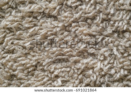 Macro shot of a beige color towel. Texture is similar to the texture of a fleecy knotted-pile carpet. Chaotic pattern of villi on fabric material.