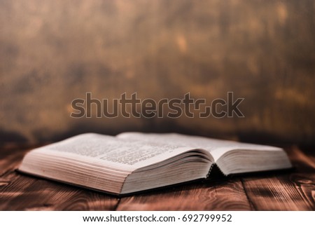 Bible and the crucifix on a wooden dark table. Beautiful gold background.Religion concept.