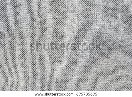 Gray knitted carpet closeup. Textile texture grey color, detailed warm yarn background. Natural woolen fabric, sweater fragment.
