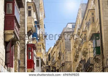 A typical street in Valletta, lined up with limestone houses and colourful bright traditional balconies.