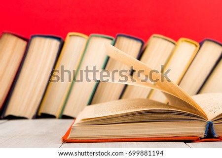 education and wisdom concept - open book on wooden table, red background