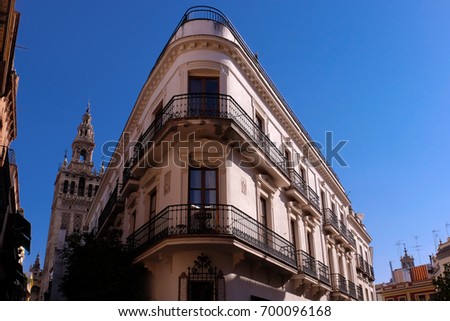 Angular building in Seville (Spain) with the cathedral in the background and blue evening sky