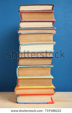 A large stack of books on a table on a blue background.