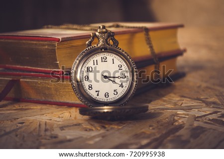 Open pocket watch and a stack of books
