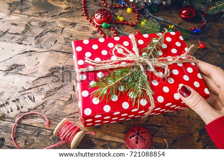 Woman's hands give wrapped christmas or other holiday handmade gift box in paper. Present box, decoration on wooden table, top view with copy space