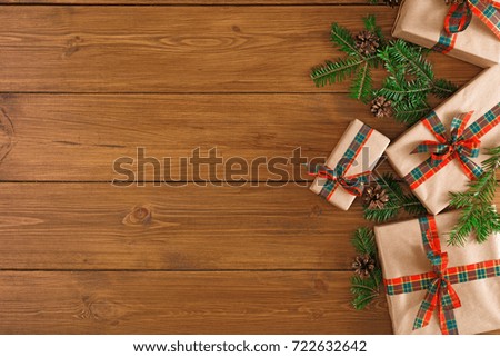 Gift boxes and fir tree twigs border, top view with copy space on wood table background. Frame of colored packages with red, green ribbons for christmas, valentine day or birthday
