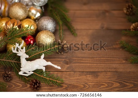 Christmas festive background with beautiful deer, golden balls and pine cons on wooden deck table, toned photo
