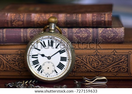 Old pocket watch and old books on a wooden table