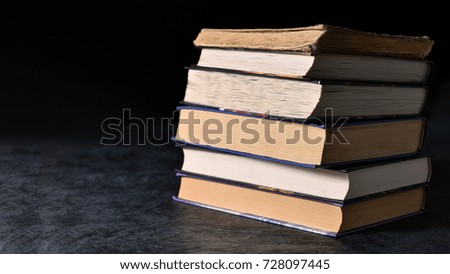 The pile of books lies on the table on a dark background